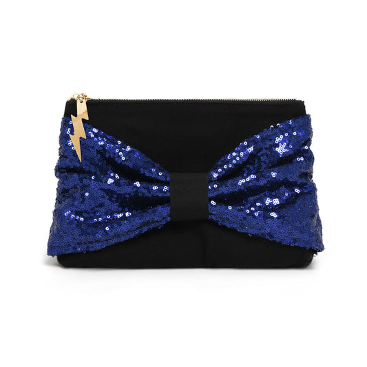 A navy clutch bag featuring a large, voluminous bow made of royal blue sequins, with a small gold lightning-bolt charm on the zipper pull, set against a plain white background.