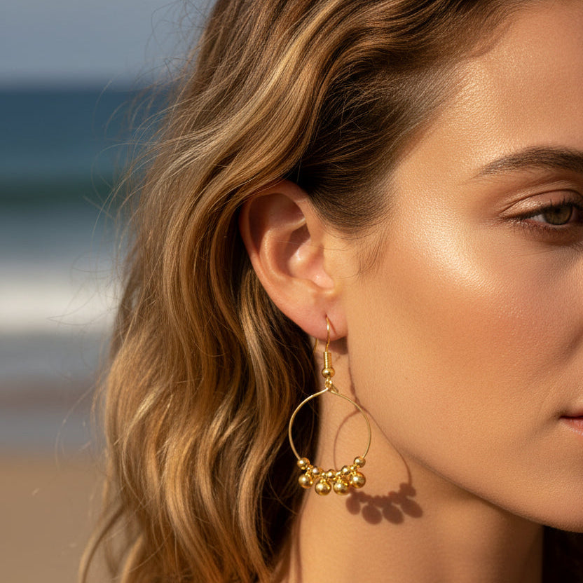 Gold hoop earrings with dangling beads on a white background