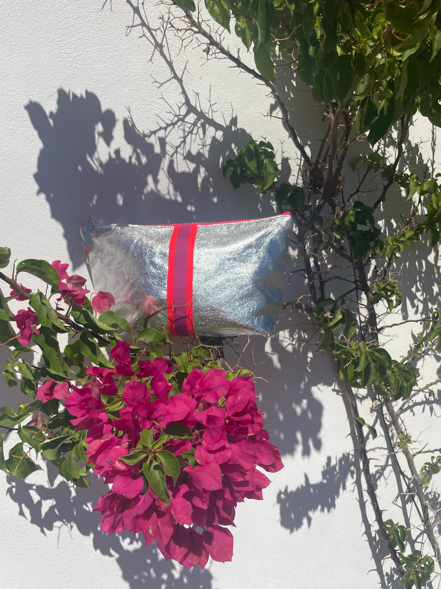 Silver bag with red ribbon and pink flowers on a light background