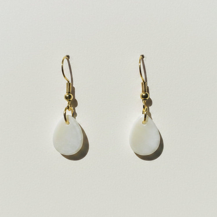 Pair of white teardrop earrings with gold hooks on a light gray background