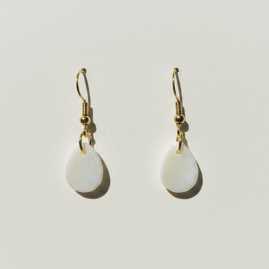 Pair of white teardrop earrings with gold hooks on a light gray background