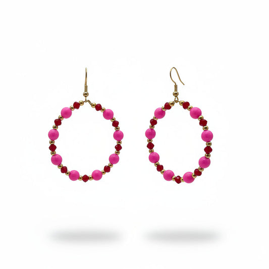 Pink and dark red beaded hoop earrings with gold hooks, displayed on a black metal stand against a light gray background.