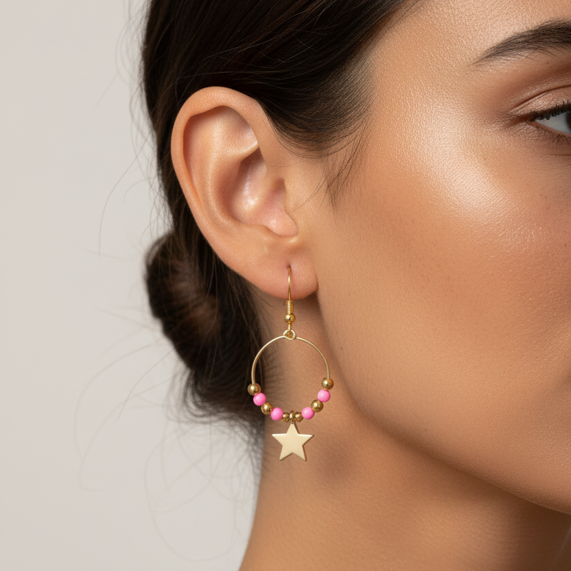 Gold hoop earrings with pink beads and star charms on a white background